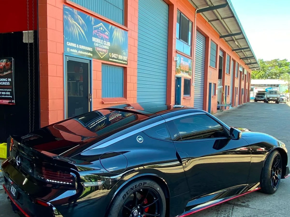 Freshly detailed glossy black sports car outside the Mobile Club Cars Cairns workshop